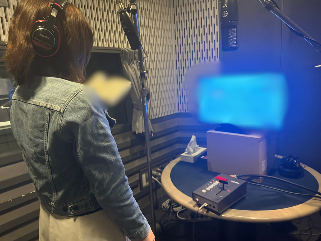 アフレコスタジオでヘッドフォンを装着し、モニターを見ながら収録に挑む髙松千波さん